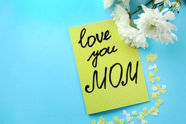 Karte mit den Worten "love you mom" und Blumen auf farbigem Hintergrund. Muttertagsfeier — Stockfoto