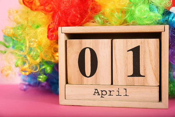 Block calendar and rainbow wig on table. April fool's day celebration — Stock Photo, Image