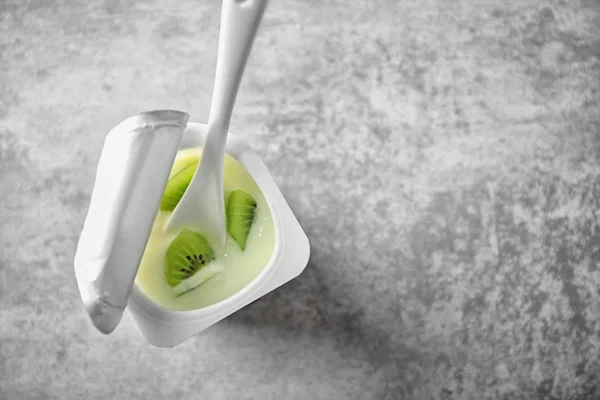 Plastic cup with yummy kiwi yogurt on table — Stock Photo, Image