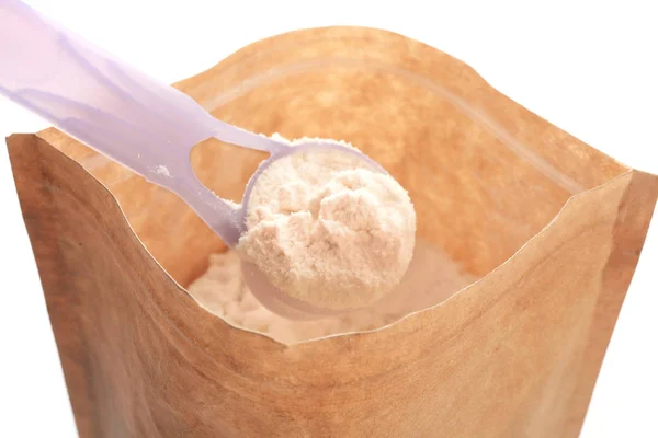 Measuring scoop with protein powder over packaging on white background — Stock Photo, Image