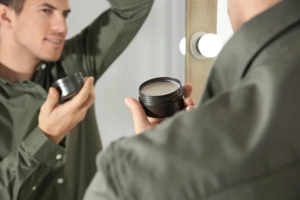 Bonito jovem aplicando argila para o cabelo perto do espelho em casa — Fotografia de Stock
