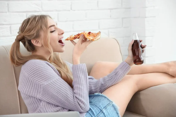 Attraktiva hipster flicka med välsmakande pizza och flaska cola inomhus — Stockfoto