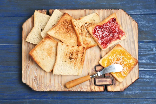 Wooden board with toasted bread on table — Stock Photo, Image