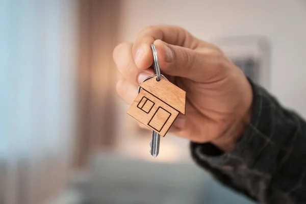 Homme tenant la clé de la maison sur fond flou, gros plan — Photo