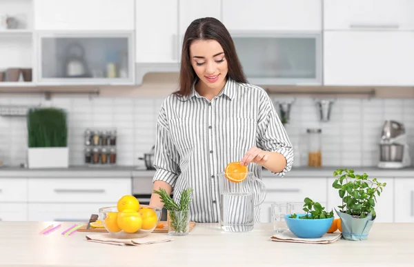 Jovem mulher preparando limonada saborosa na cozinha — Fotografia de Stock