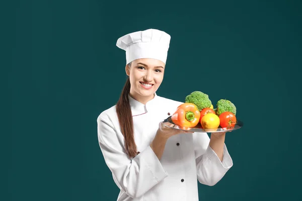 Prachtige vrouwelijke chef-kok plaat met groenten houden op kleur achtergrond — Stockfoto