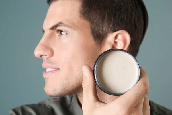 Handsome young man with clay for hair on color background — Stock Photo, Image