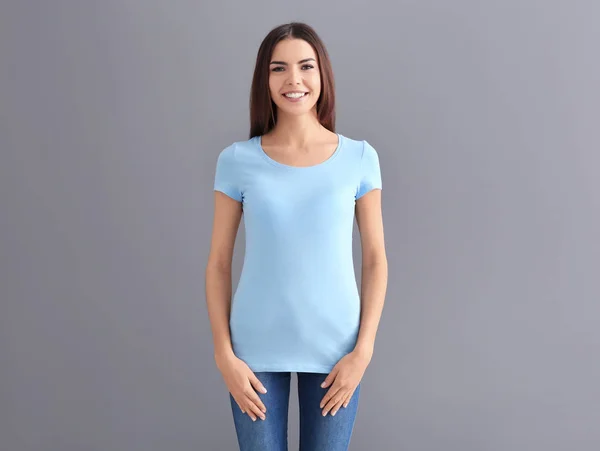 Bella giovane donna in elegante t-shirt su sfondo grigio. Mockup per il design — Foto Stock