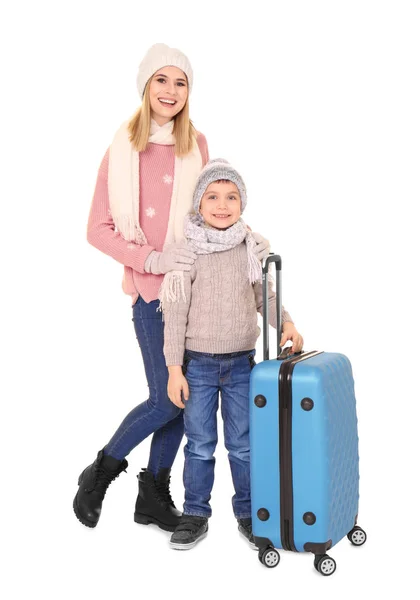 Lindo niño pequeño con madre y equipaje sobre fondo blanco. Listo para vacaciones de invierno —  Fotos de Stock