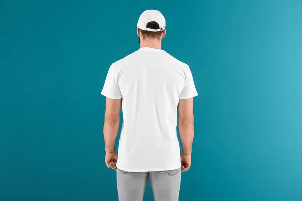 Bonito jovem em elegante camiseta branca sobre fundo de cor. Mockup para design — Fotografia de Stock