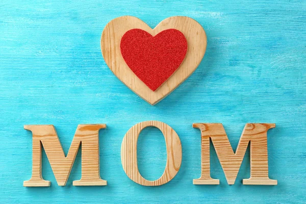 Word "Mom" and heart figure on wooden background. Mother's day celebration — Stock Photo, Image