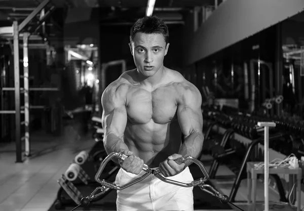 Entrenamiento muscular joven culturista en gimnasio, efecto blanco y negro — Foto de Stock