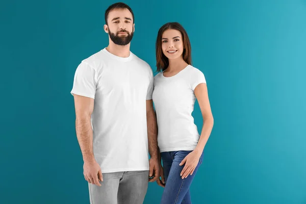 Młody mężczyzna i kobieta w stylowe białe koszulki na kolor tła. Makieta do projekt — Zdjęcie stockowe
