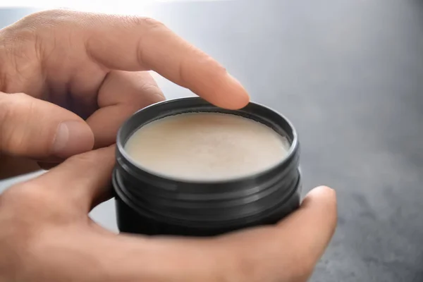 Mãos masculinas com jarra de barro para cabelos em fundo cinza, close-up — Fotografia de Stock