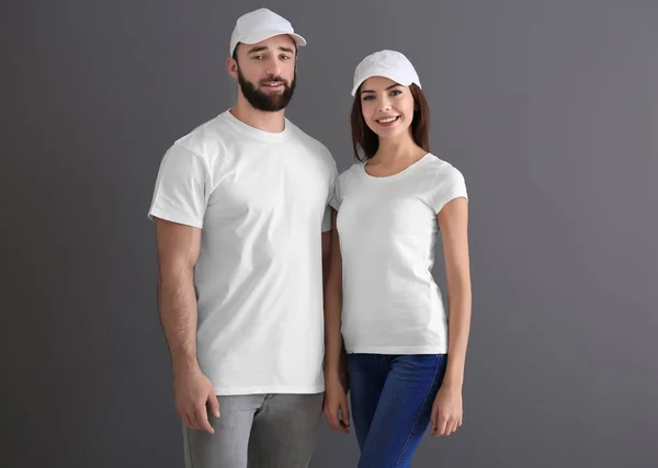 Jeune homme et femme en t-shirts blancs élégants sur fond gris. Maquette pour le design — Photo