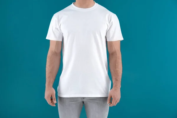 Beau jeune homme en t-shirt blanc élégant sur fond de couleur. Maquette pour le design — Photo