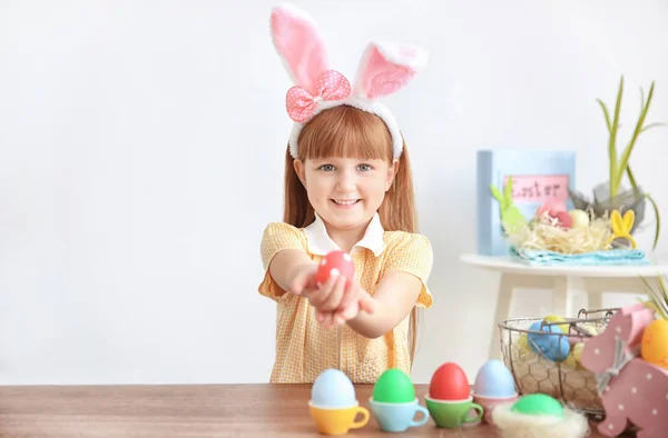 Söt liten flicka med bunny öron holding ljusa påskägg inomhus — Stockfoto