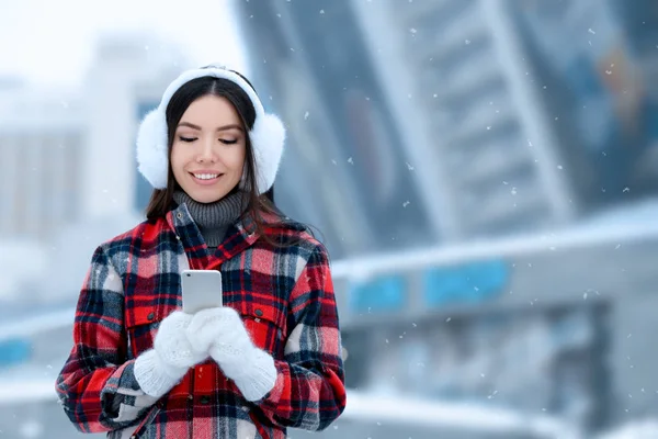 Красивая молодая женщина с мобильным телефоном на открытом воздухе в зимний день — стоковое фото