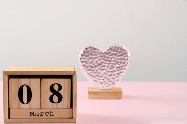 Wooden block calendar and decorative heart figure on table. International Women's Day celebration — Stock Photo, Image