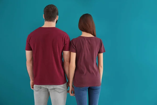 Jovem e mulher em camisetas elegantes no fundo de cor. Mockup para design — Fotografia de Stock