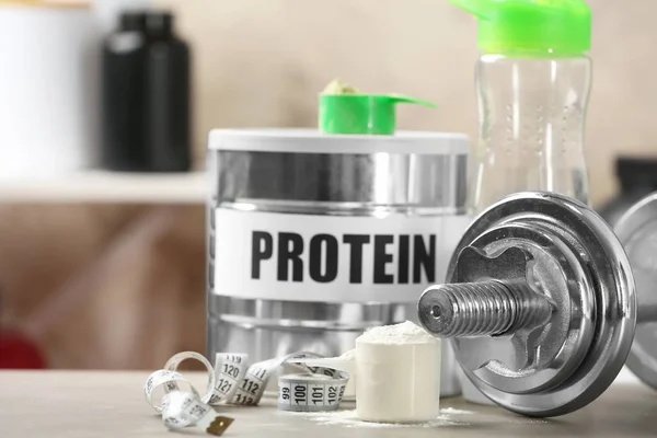 Složení s proteinový prášek a činka na stole — Stock fotografie