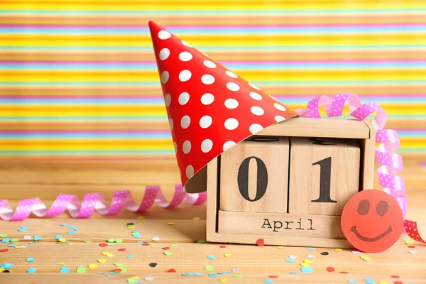 Block calendar, party cap and confetti on table. April fool's day celebration — Stock Photo, Image
