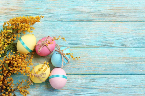 Easter eggs with mimosa flowers on wooden background — Stock Photo, Image