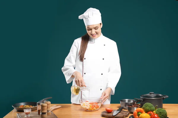 Güzel kadın Şef salatası renk arka plan karşı masada yağı ekleyerek — Stok fotoğraf