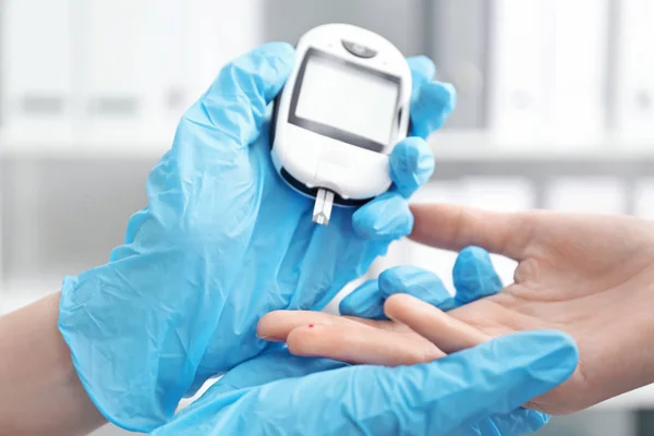 Dokter van testen patiënt bloedglucose niveau met digitale glucometer op onscherpe achtergrond. Diabetes controle — Stockfoto