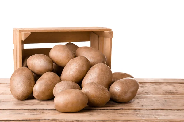 Overturned wooden container with fresh raw potatoes on table against white background — Stock Photo, Image