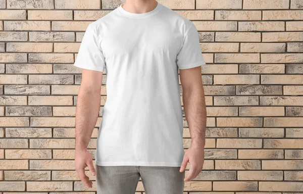 Bonito jovem em elegante t-shirt branca perto da parede de tijolo. Mockup para design — Fotografia de Stock