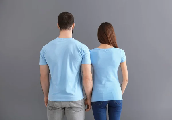 Ung man och kvinna i snygga t-shirts på grå bakgrund. Mockup för design — Stockfoto