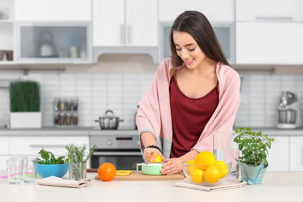 Молодая женщина готовит вкусный лимонад на кухне — стоковое фото