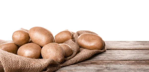 Verse rauwe aardappelen op houten tafel tegen witte achtergrond — Stockfoto