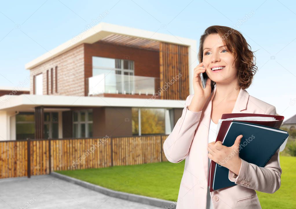 Real estate agent talking on phone in front of house outdoors