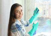 junge Frau putzt Fenster im Haus