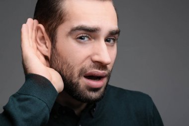 Gri arka plan üzerinde işitme sorunu olan genç adam