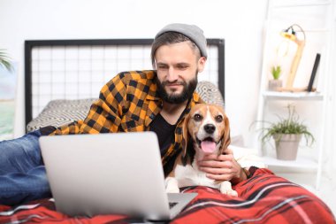 Yakışıklı genç hipster köpeğiyle evde yatağında dinleniyor