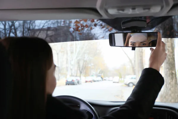 Mulher ajustando espelho retrovisor no carro — Fotografia de Stock