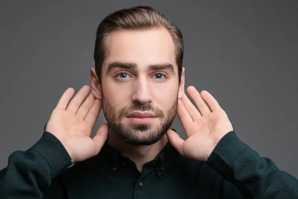 Jonge man met hoorzitting probleem op grijze achtergrond — Stockfoto