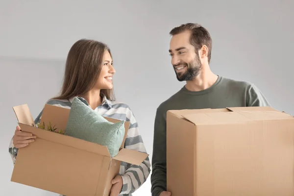 Pareja joven con cajas móviles sobre fondo gris —  Fotos de Stock