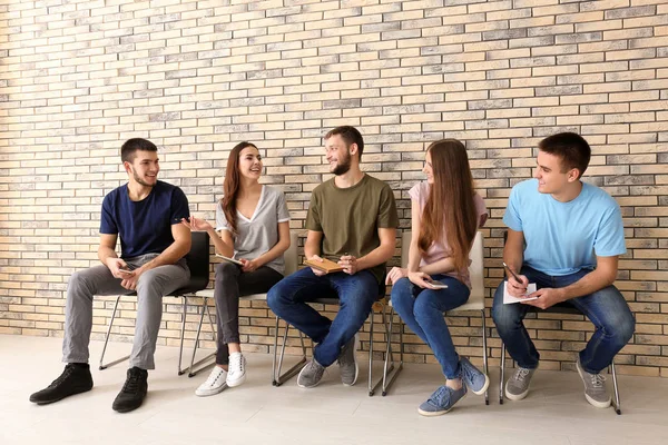 Grupo de jóvenes sentados en sillas juntos, en el interior. Concepto de unidad —  Fotos de Stock