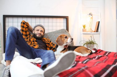 Yakışıklı genç hipster köpeğiyle evde yatağında dinleniyor