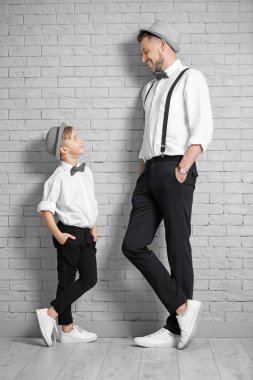 Baba ve oğul tuğla duvarın karşısında şık elbiseli