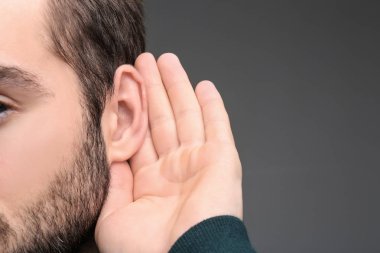 Gri arka plan, closeup işitme sorunu olan genç adam