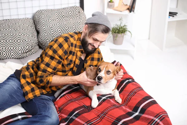 Guapo joven hipster con su perro descansando en la cama en casa —  Fotos de Stock