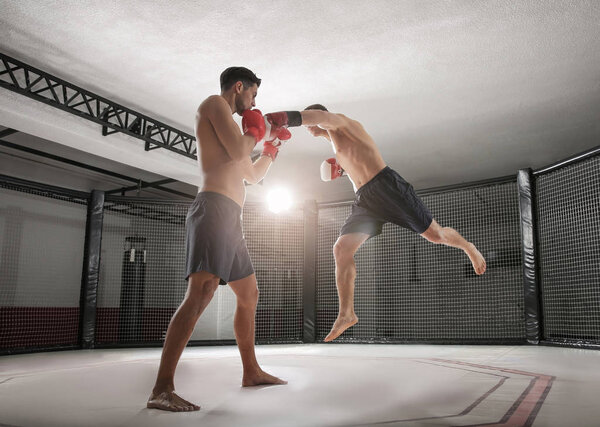 Два сильных кикбоксера, дерущихся в спортзале
