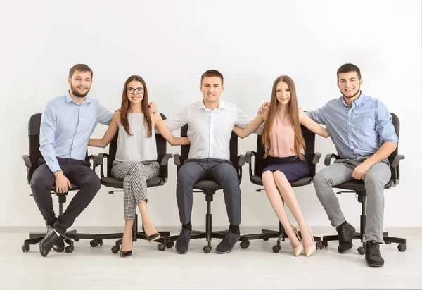 Grubu birlikte beyaz duvara sandalyelere oturan genç insanlar. Birlik kavramı — Stok fotoğraf