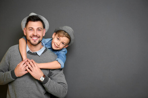 Стильные отец и сын на сером фоне
