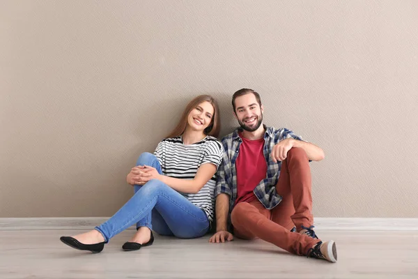 Casal jovem sentado no chão em quarto vazio. Pronto para mudar para casa nova — Fotografia de Stock